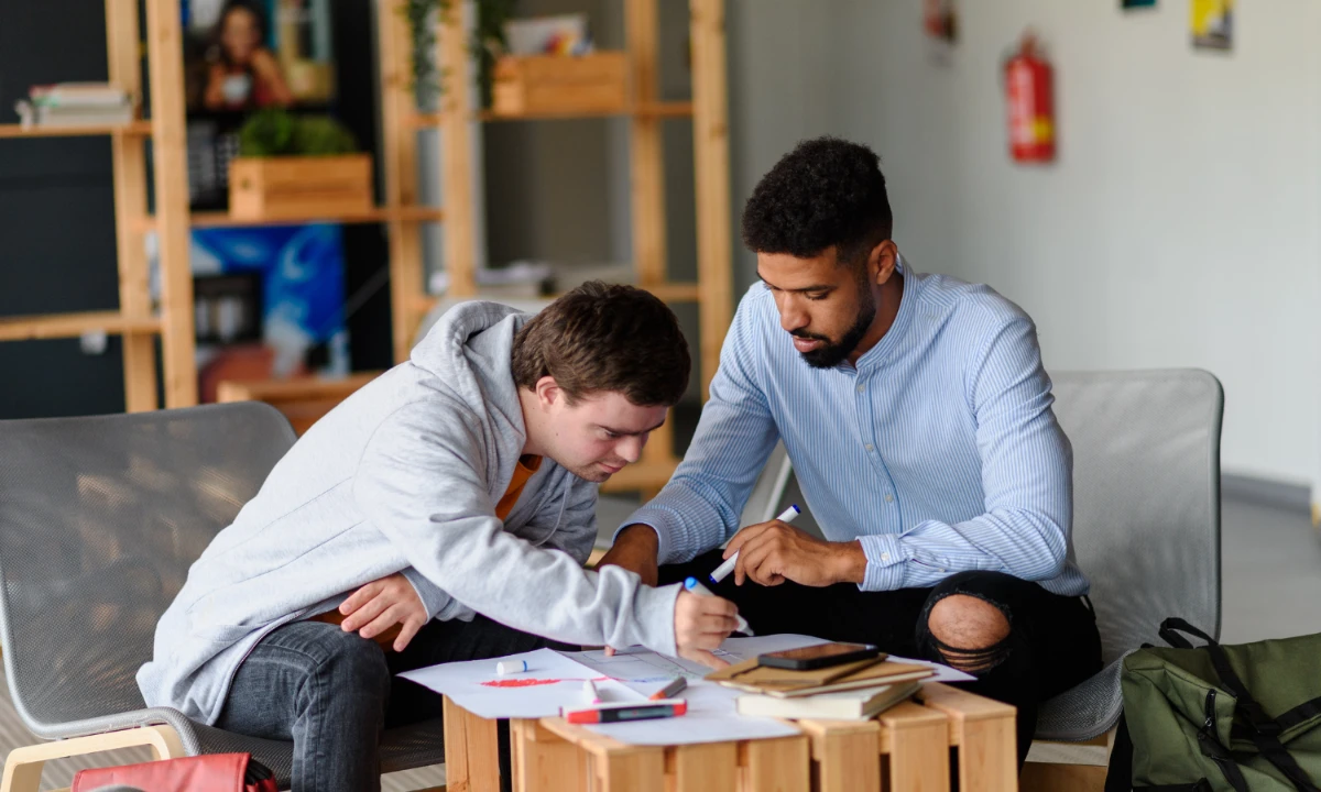 Young Man with down Syndrome Studyng with Special Educator Teacher in Special Education Classroom -